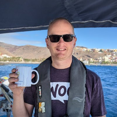 A photo of Ronald holding a coffee mug while standing on a boat.