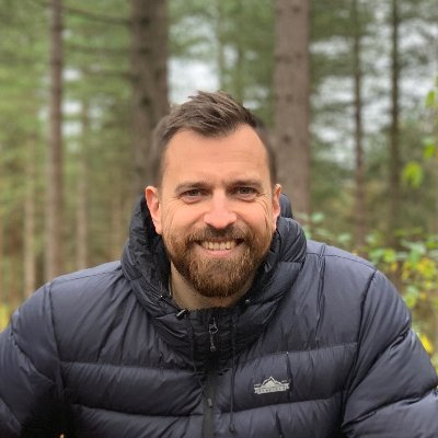 A photo of Iain Poulson smiling in a forest. 