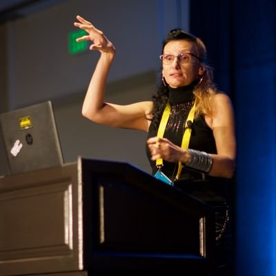 A photo of Milana Cap giving a presentation from behind a podium.