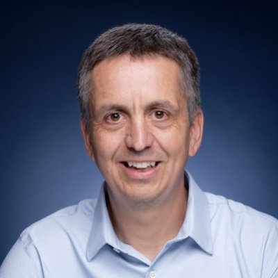 Steve Burge smiling in front of a blue background.