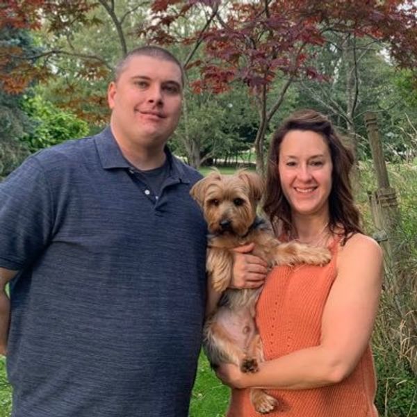 Jeff standing next to his partner, who's holding a small dog.