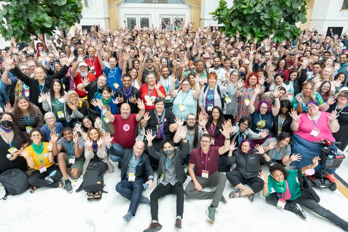 A very large crowd of people raising their hands up in the air.