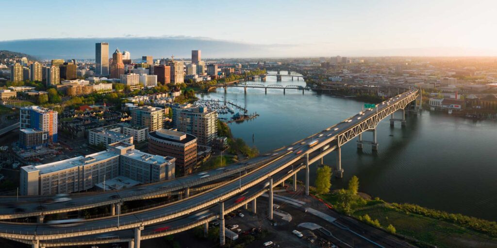 Aerial view of a city skyline with a river and bridges at sunset.